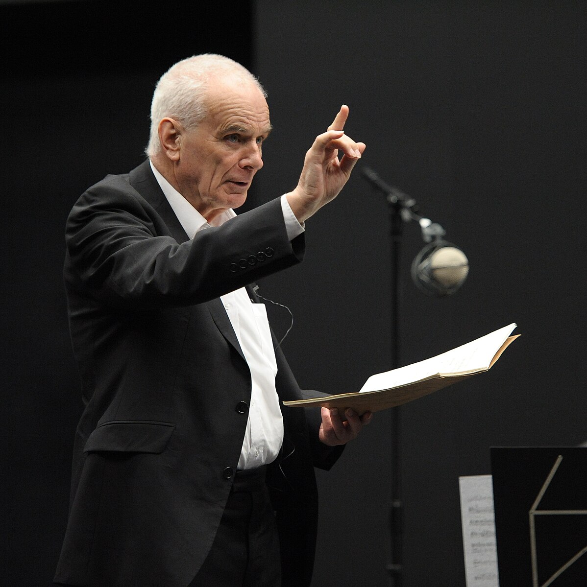 Peter Maxwell Davies holding a score and pointing his finger upward.