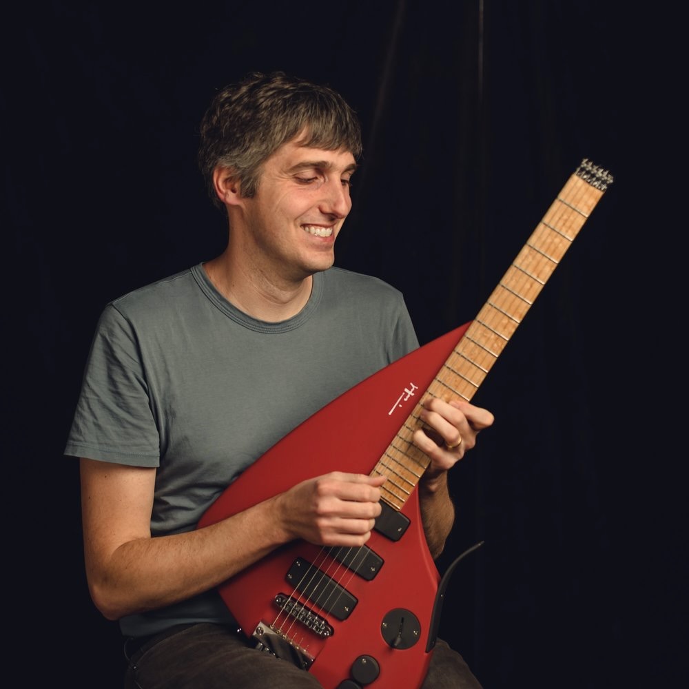 Giacomo Fiore holding a red guitar.