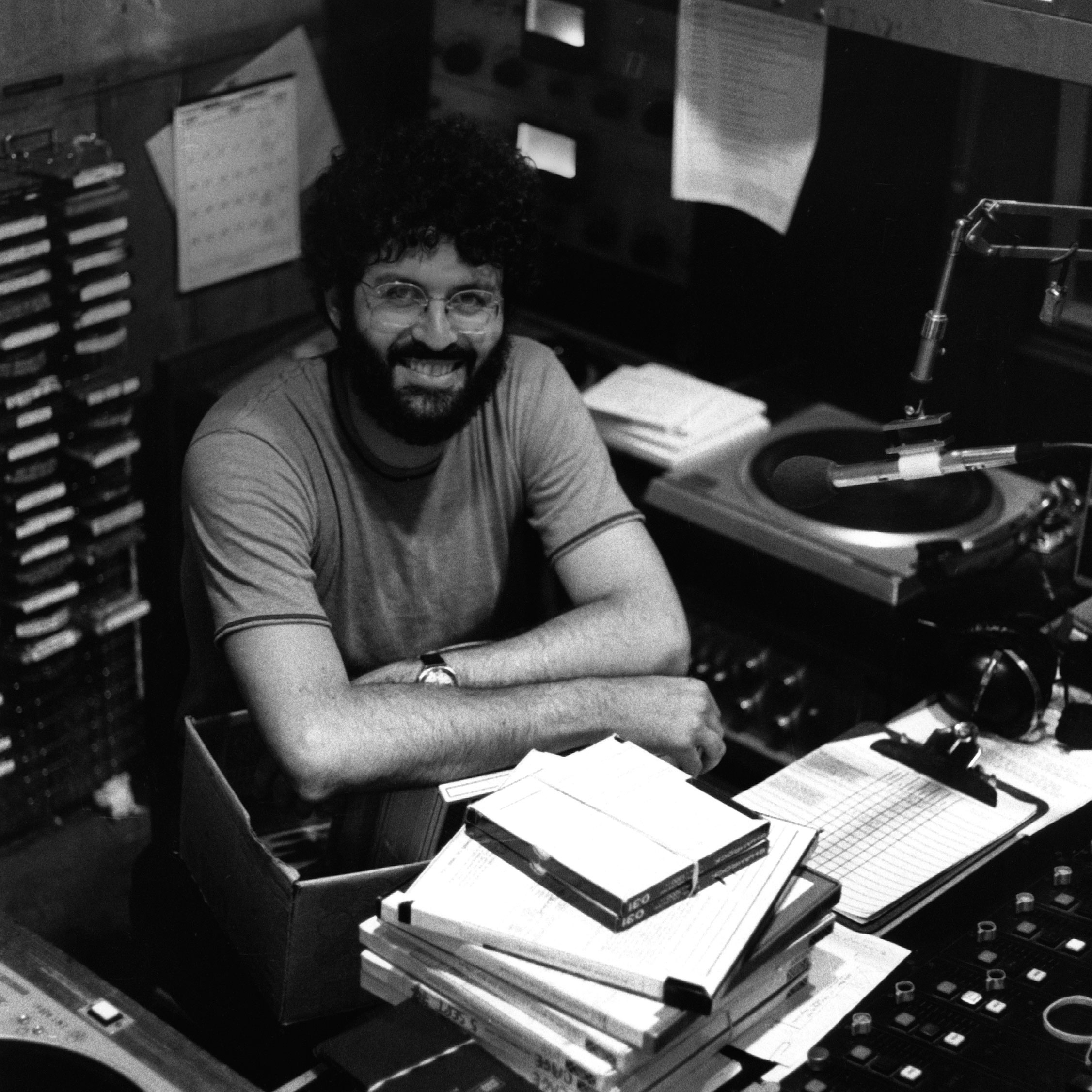 Charles Amirkhanian, head and shoulders portrait, seated, facing forward, in KPFA studio, Berkeley, California in 1979.