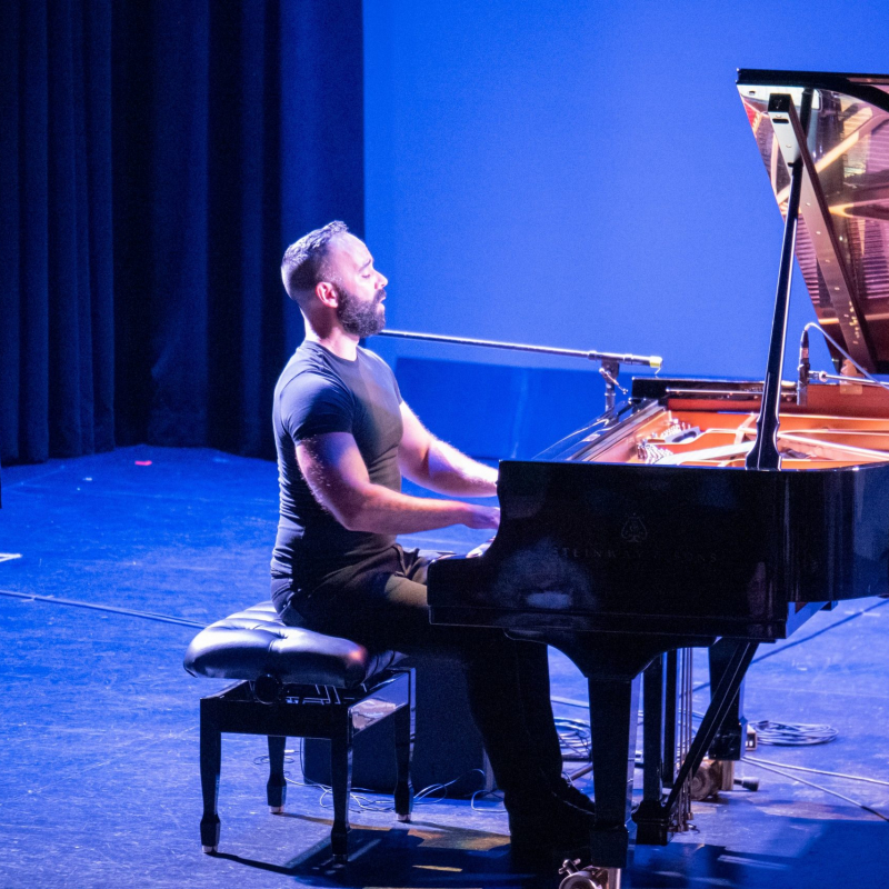 Adam Tendler playing piano on stage.